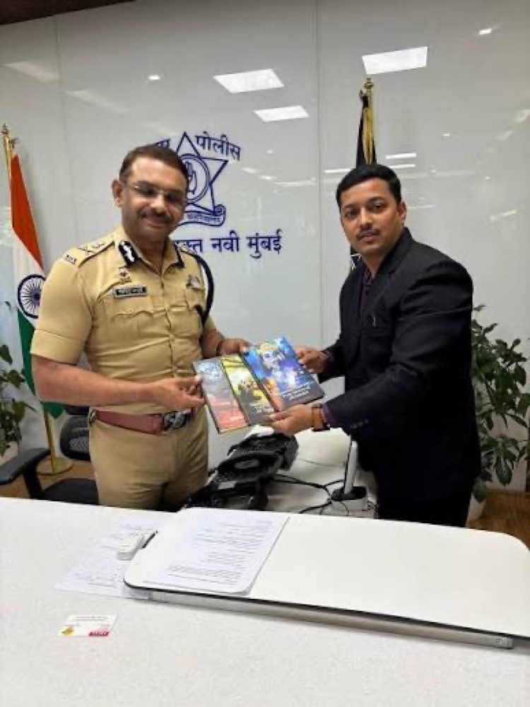 Milind Bharambe in uniform receiving a set of publications from a visitor at the Navi Mumbai Commissioner of Police office.