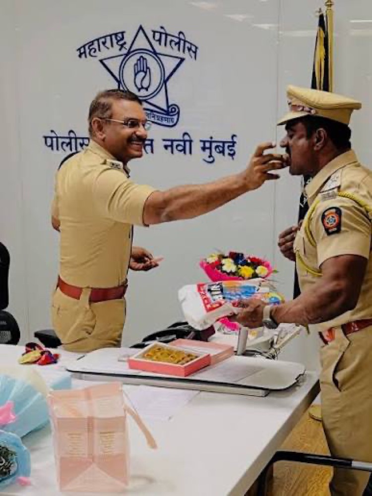 Milind Bharambe offering sweets to a police officer in a moment of felicitation at the Navi Mumbai Police Commissioner's office.